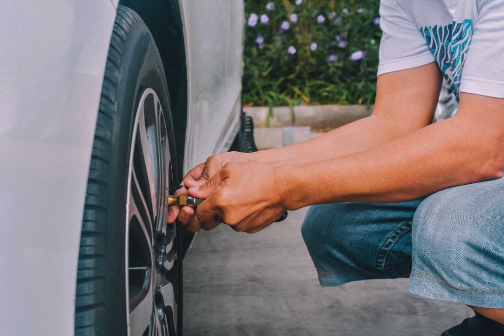 Low Section Of Man Inflating Car Tire Low Section Of Man Inflating Car Tire