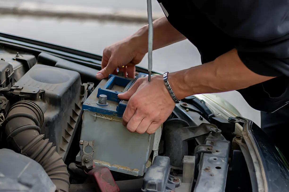 Car battery being removed from a vehicle's engine bay
