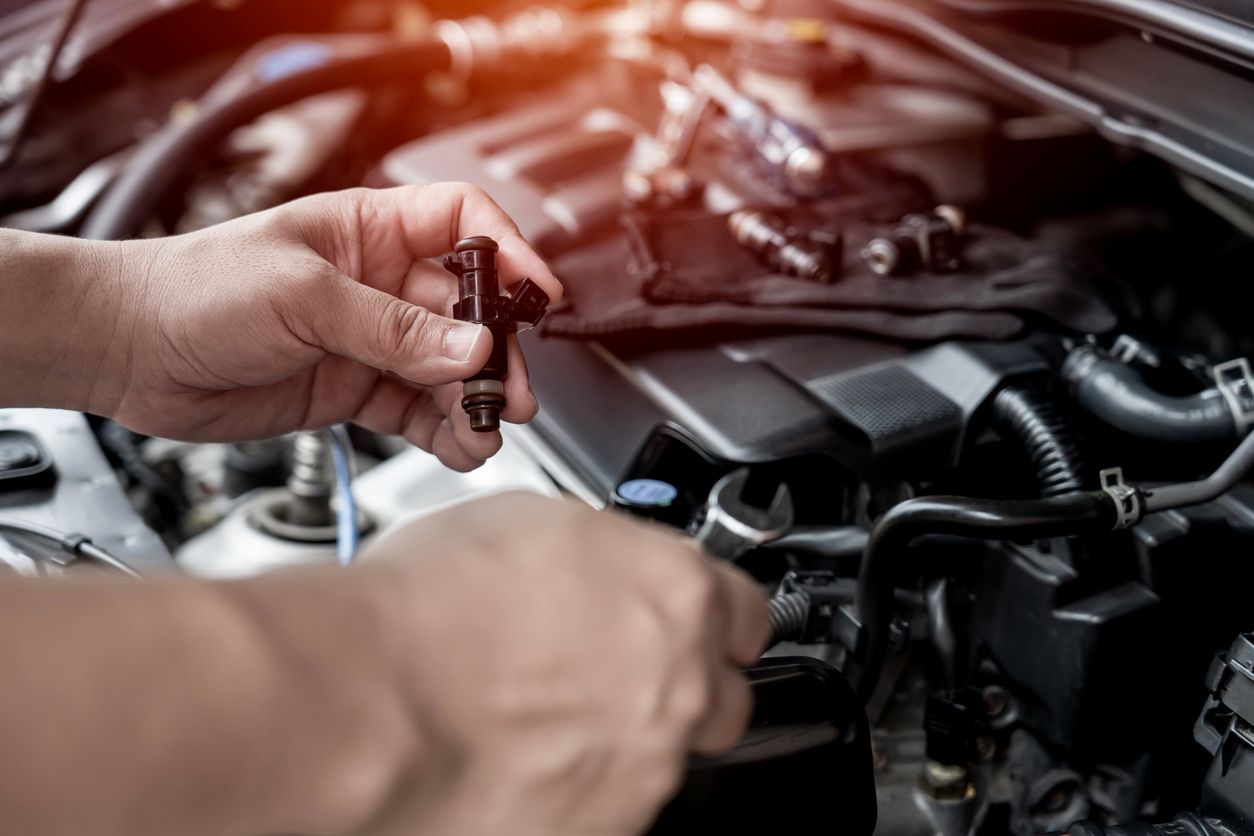 Car fuel injector being held by a technician during engine maintenance
