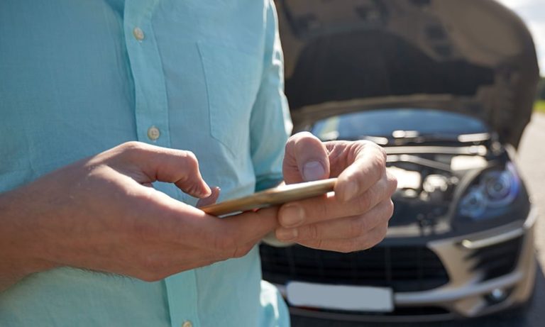 Driver using a smartphone to contact roadside assistance for a breakdown