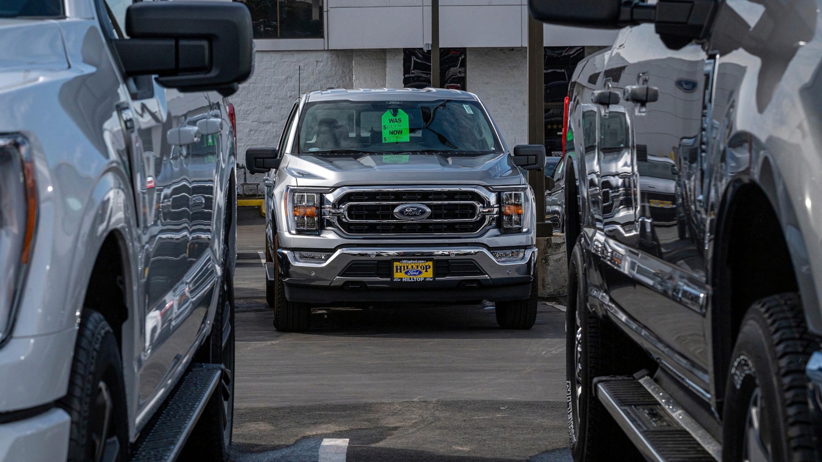 A silver Ford pickup truck with a green price tag parked in a dealership lot