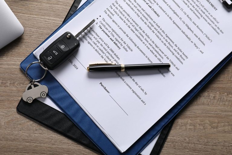 Car buyer reviewing purchase paperwork with car keys on a dealership sales desk