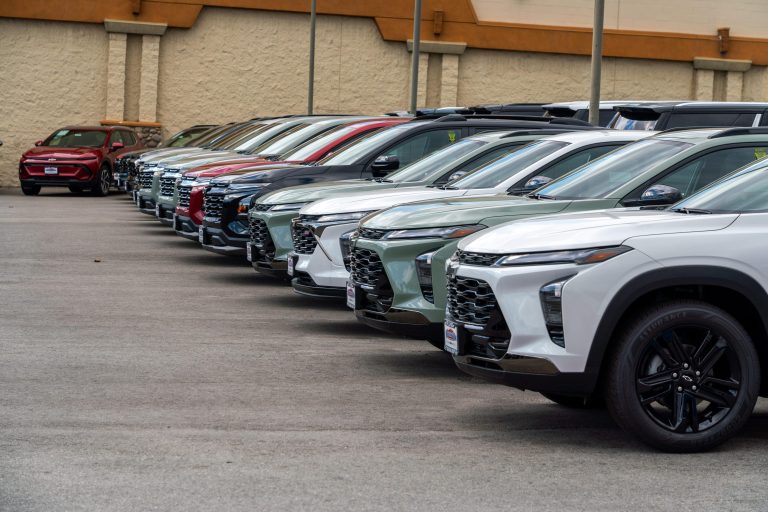 Rows of new SUVs lined up on a dealership lot awaiting buyers.