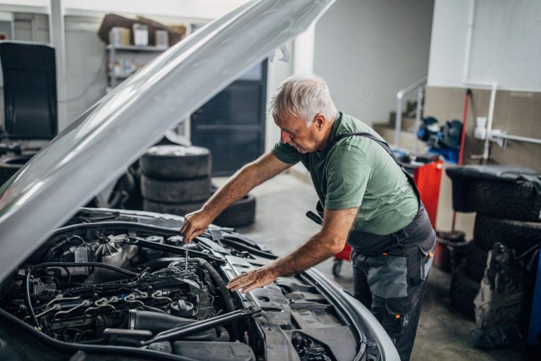 Mechanic inspecting a high-mileage vehicle inside a professional automotive repair shop