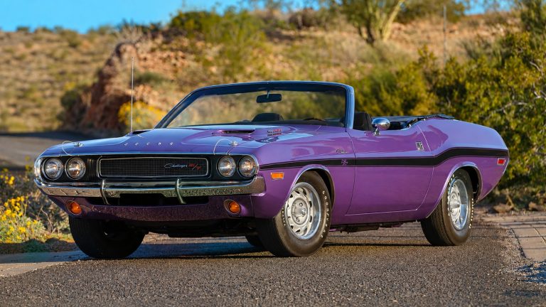 A classic purple Dodge Challenger convertible parked on a scenic road with a desert background
