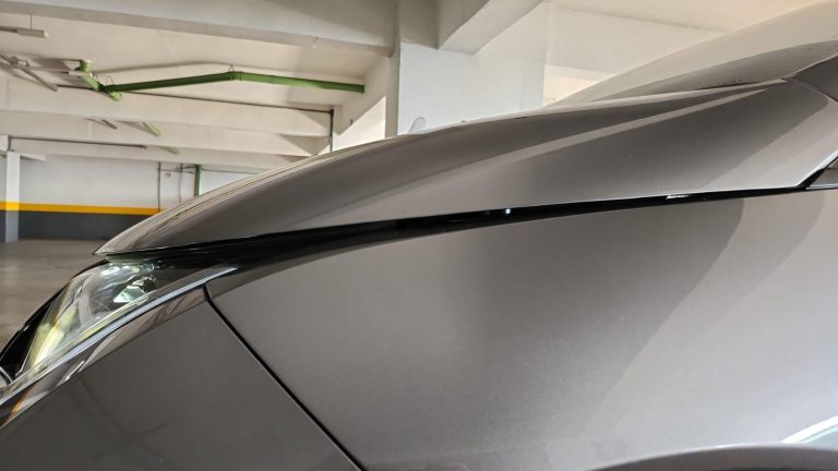 close-up view showing an uneven hood gap and misalignment on a grey car