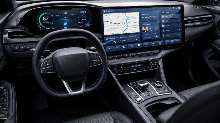 Modern car interior featuring a steering wheel and wide digital infotainment and navigation screens