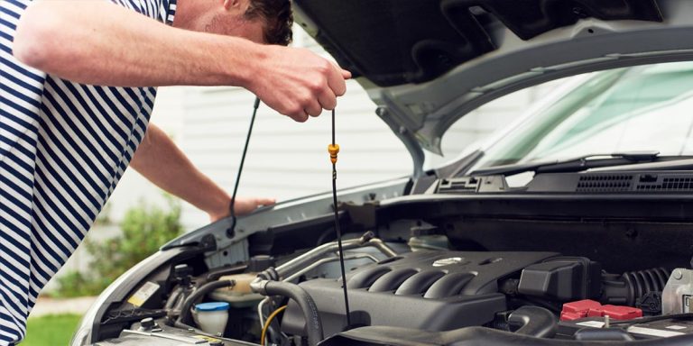 A man is trying to repair his broken car