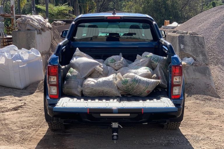 A blue pickup truck loaded with heavy sacks in its open truck bed