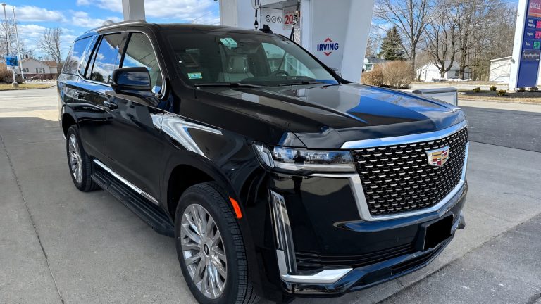 shiny black luxury SUV parked at an Irving gas station under a cloudy sky