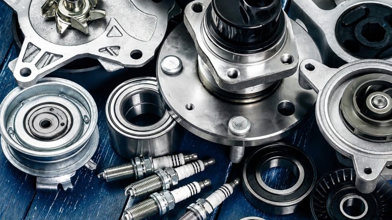 close-up shot of various new silver metallic car parts on a blue surface