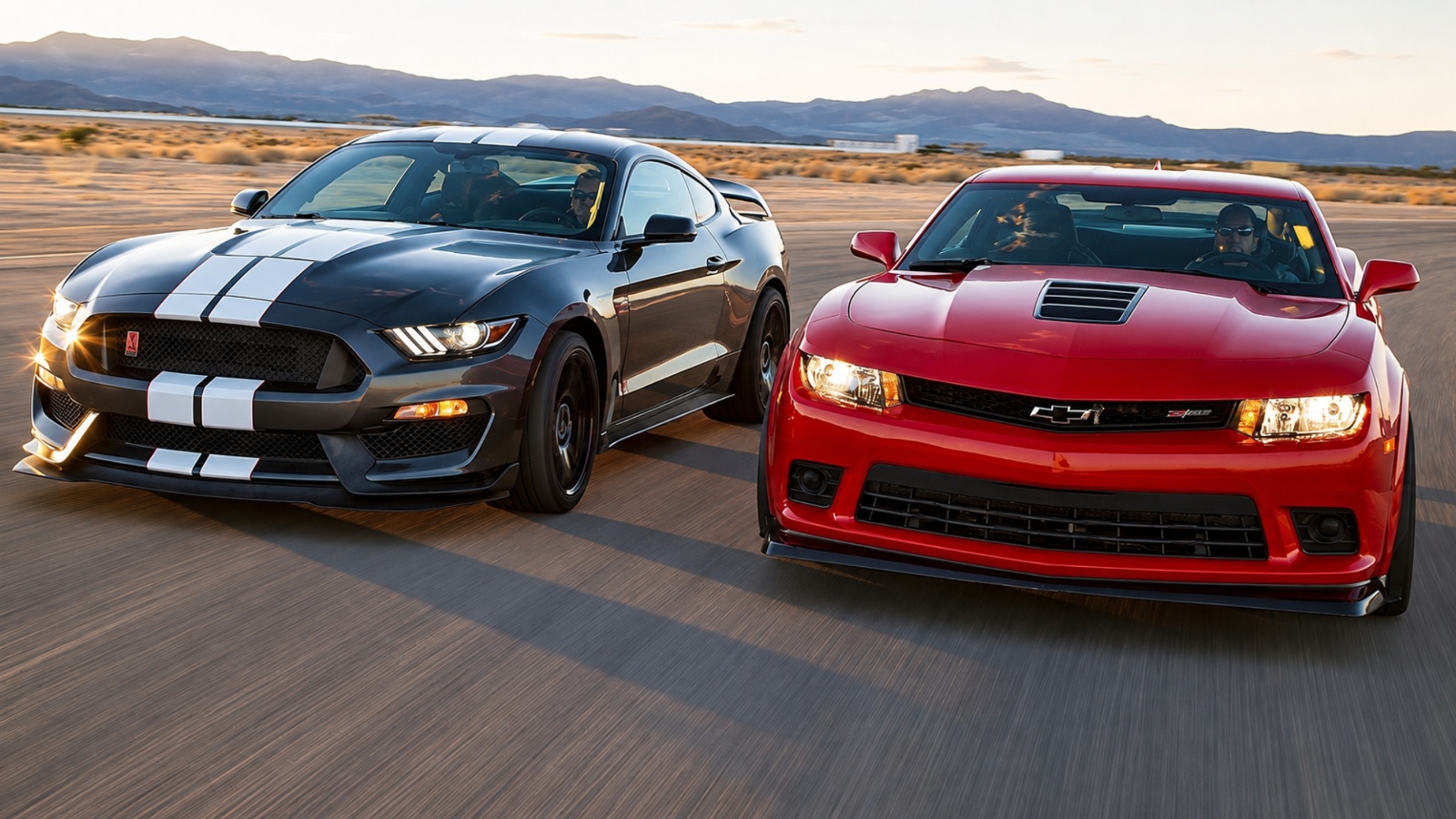 dark gray Shelby Mustang and a red Chevrolet Camaro driving on a dry track