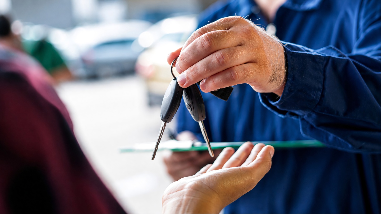 Mechanic in blue shirt handing car keys to a customer