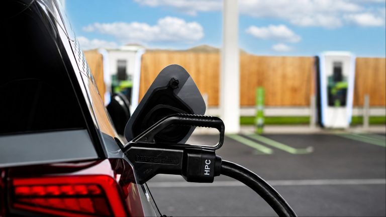 An electric vehicle plugged into an HPC charging station outdoors