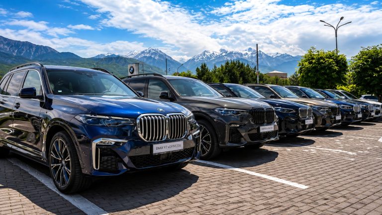 row of luxury blue and dark SUVs parked outside against a mountain backdrop