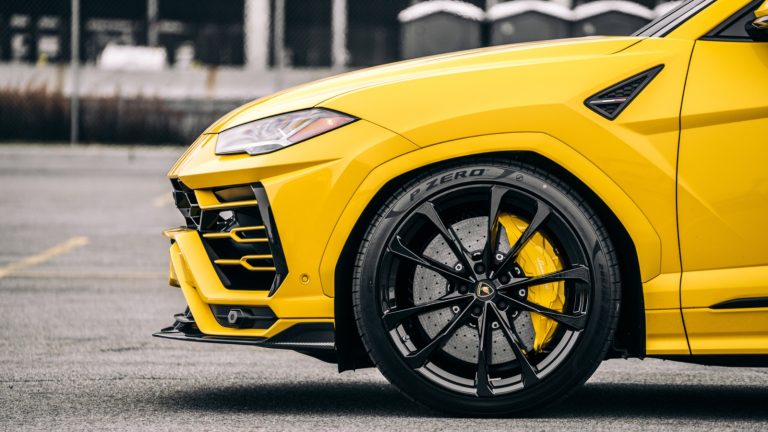close-up of a bright yellow Lamborghini SUV highlighting its large brake rotors and wheels
