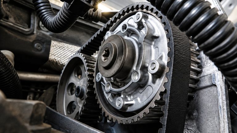 close-up view of a car engine compartment highlighting the timing belt and pulleys