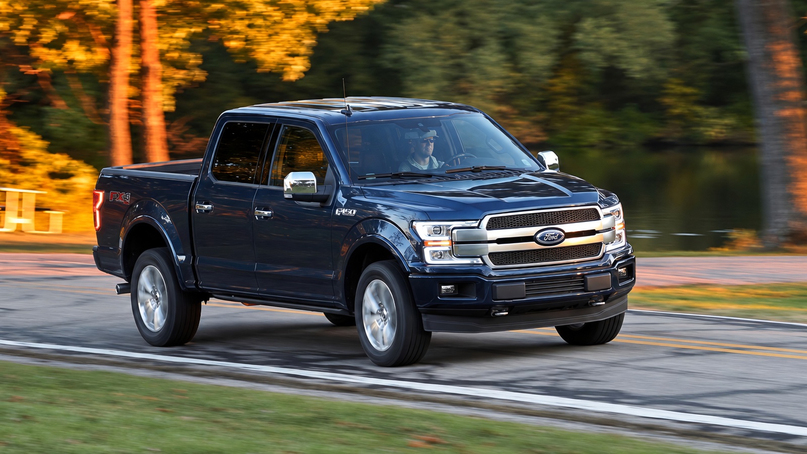 modern dark blue Ford F-150 pickup truck driving along a scenic parkway