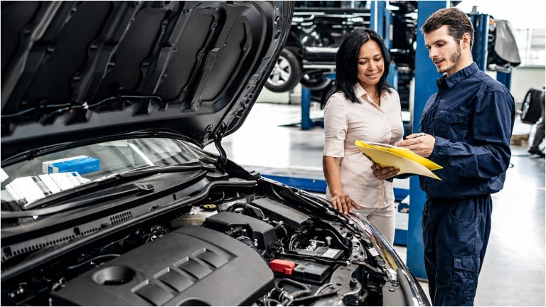 mechanic reviewing car paperwork with a female customer in a repair shop