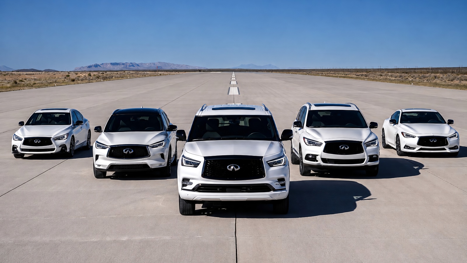 Five white Infiniti luxury vehicles parked in a line on a wide open tarmac runway.