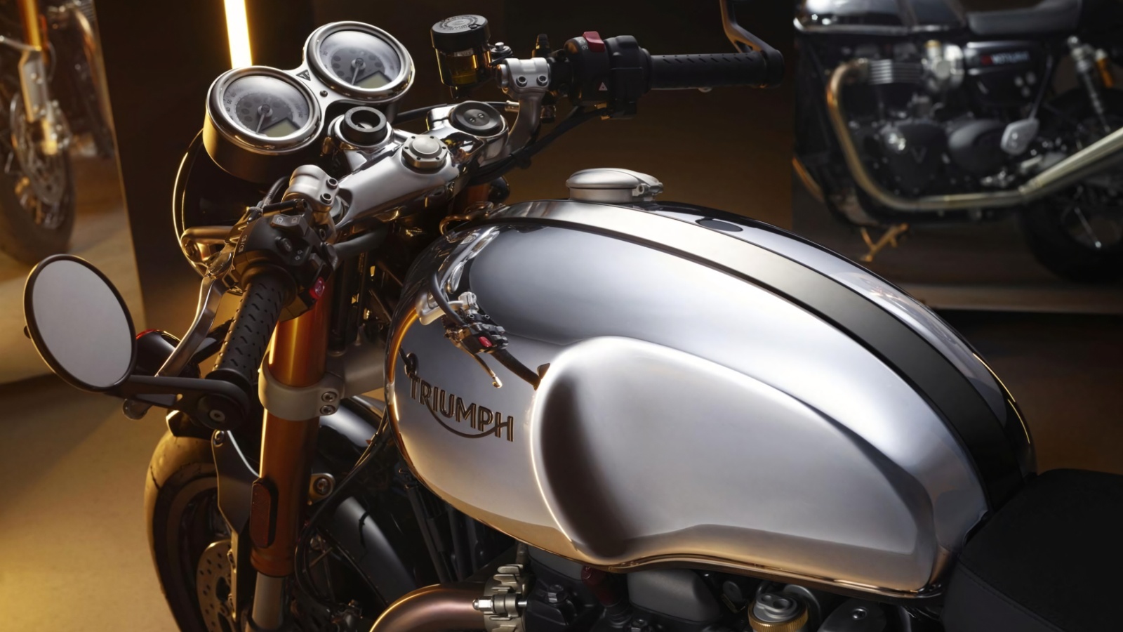 Close-up view of the chrome fuel tank and handlebars of a Triumph motorcycle