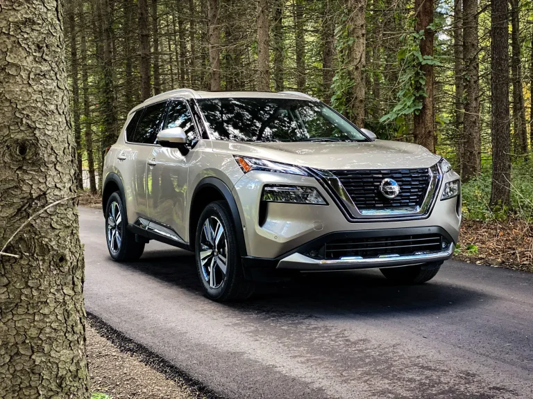 A Nissan is cruising on a forest road