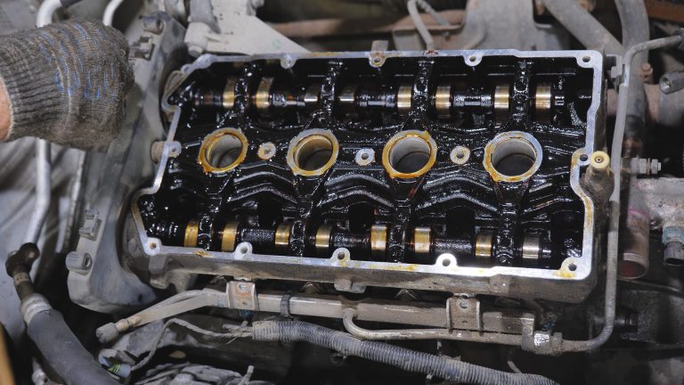 Mechanic inspecting engine internals with visible oil sludge buildup