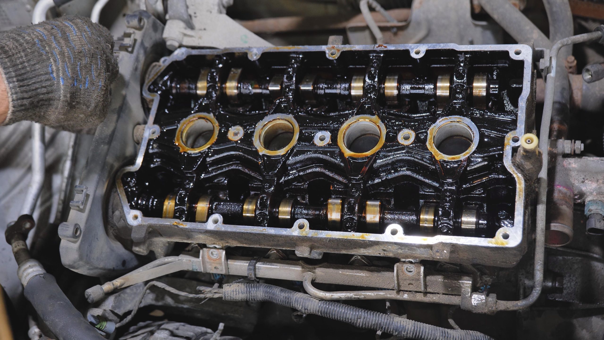 Mechanic inspecting engine internals with visible oil sludge buildup