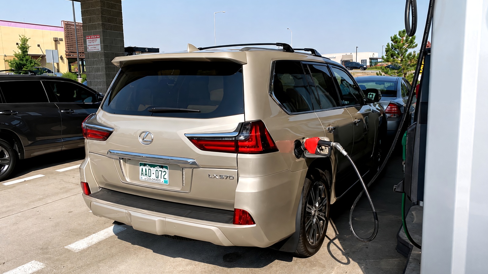 gold Lexus LX 570 SUV refueling at a gas station