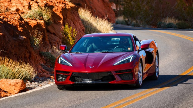 modern red sports car driving on a scenic winding mountain road between red rocks.