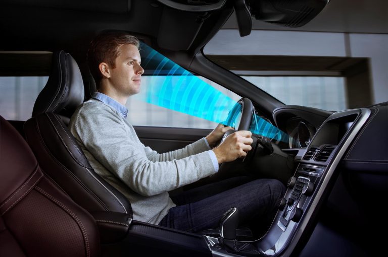 A driver sitting inside a car with a blue graphical scanner monitoring his face