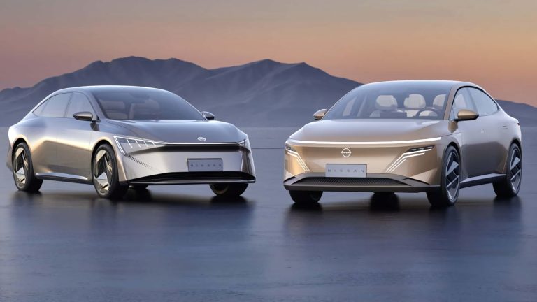 Two sleek, modern silver and gold Nissan concept sedans parked against a mountain backdrop