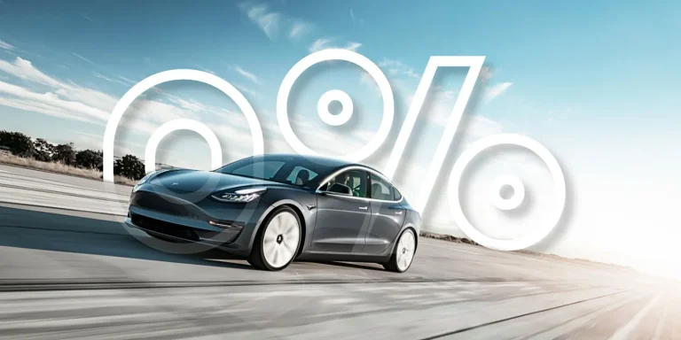 A gray electric car driving past a large white percent sign