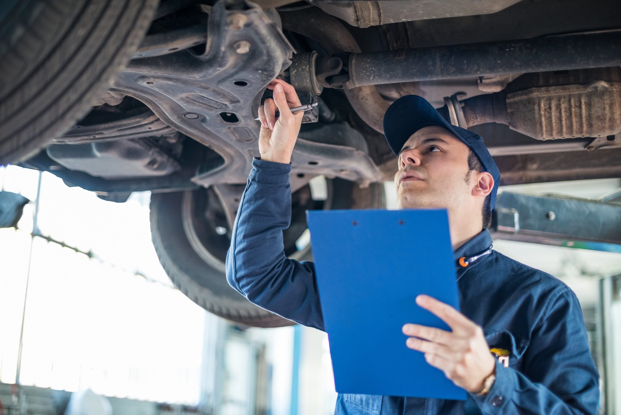 Auto mechanic inspecting the underside of a raised car