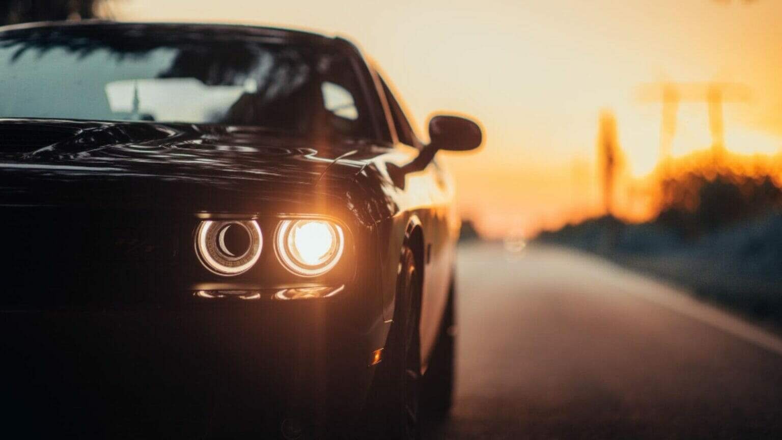 Black Dodge Challenger Hellcat's headlights glowing brightly