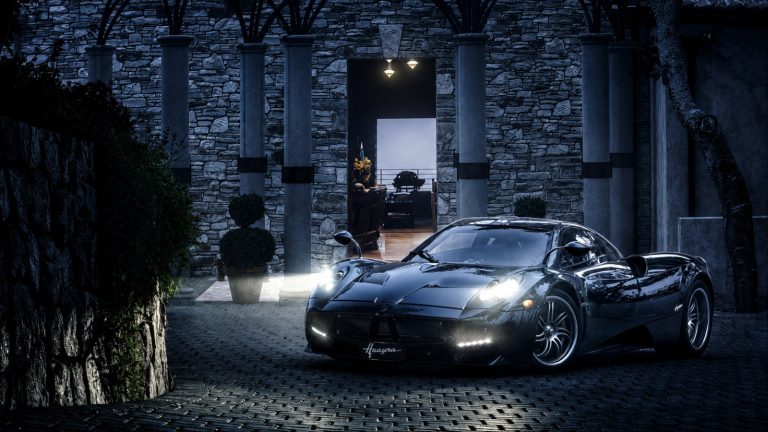 Black Pagani Huayra parked outside a luxury stone mansion at night