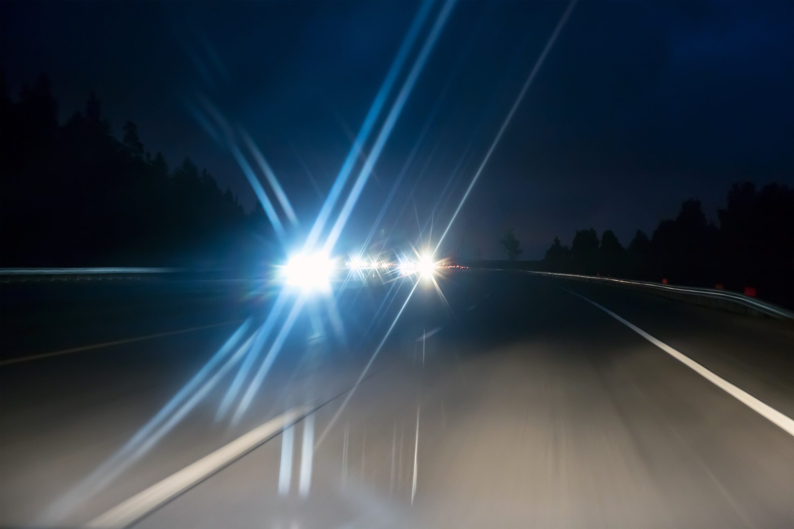 Bright glare of oncoming headlights on a dark