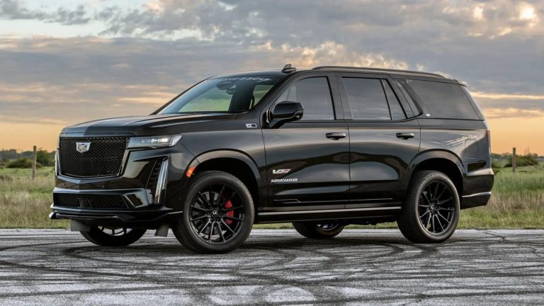 A sleek black Cadillac Escalade parked outdoors under a cloudy sky