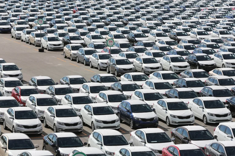 Many cars are standing in an open warehouse