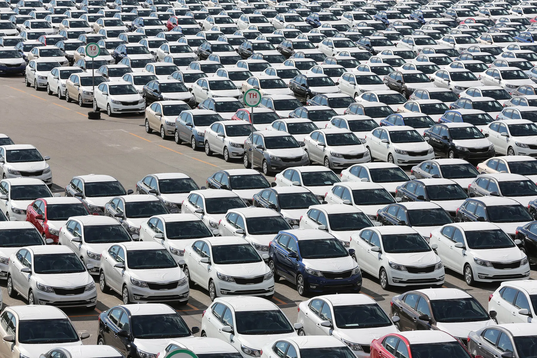 Many cars are standing in an open warehouse