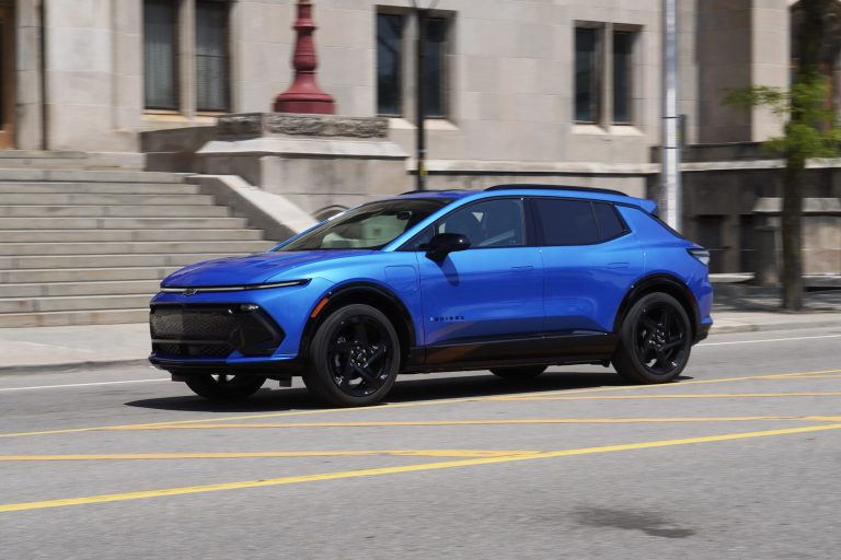 A blue Chevrolet Equinox is cruising at high speed on city road