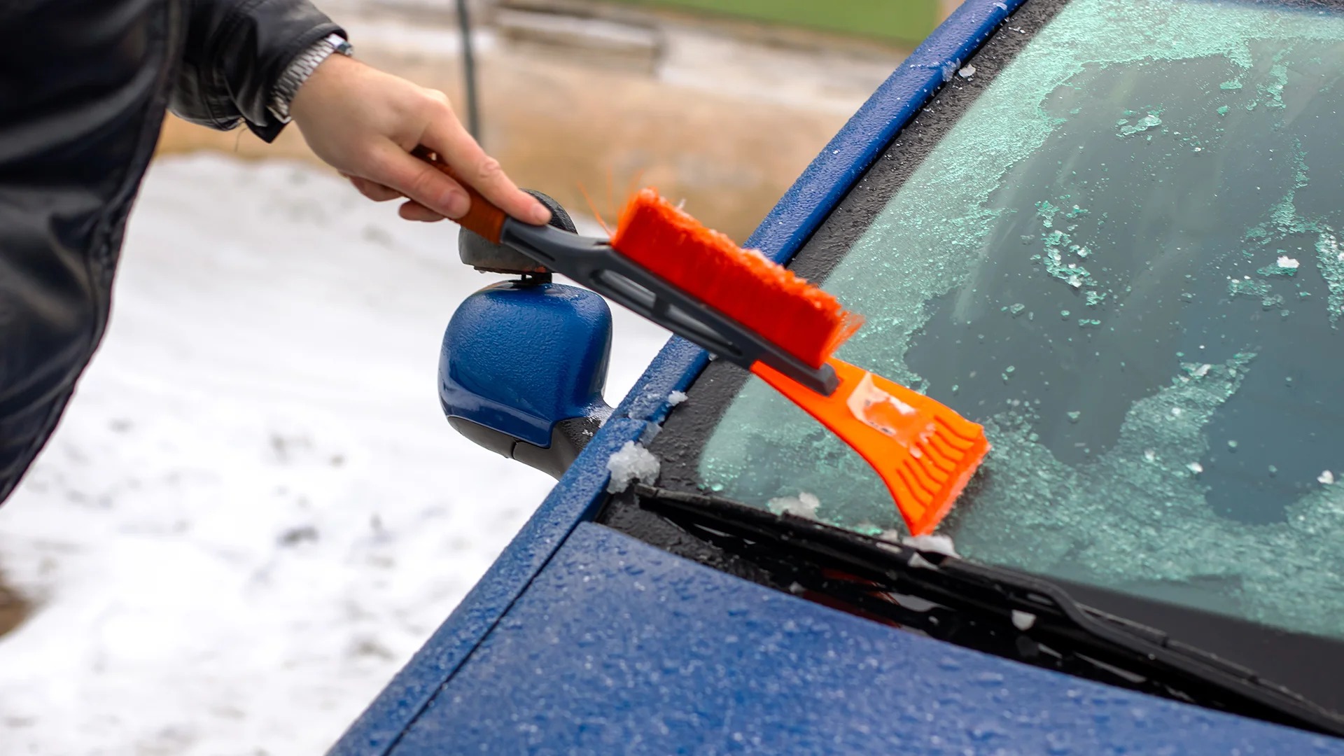 Clearing frost from a blue car's windshield