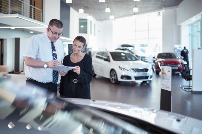 A couple is looking at the documents in a car dealership