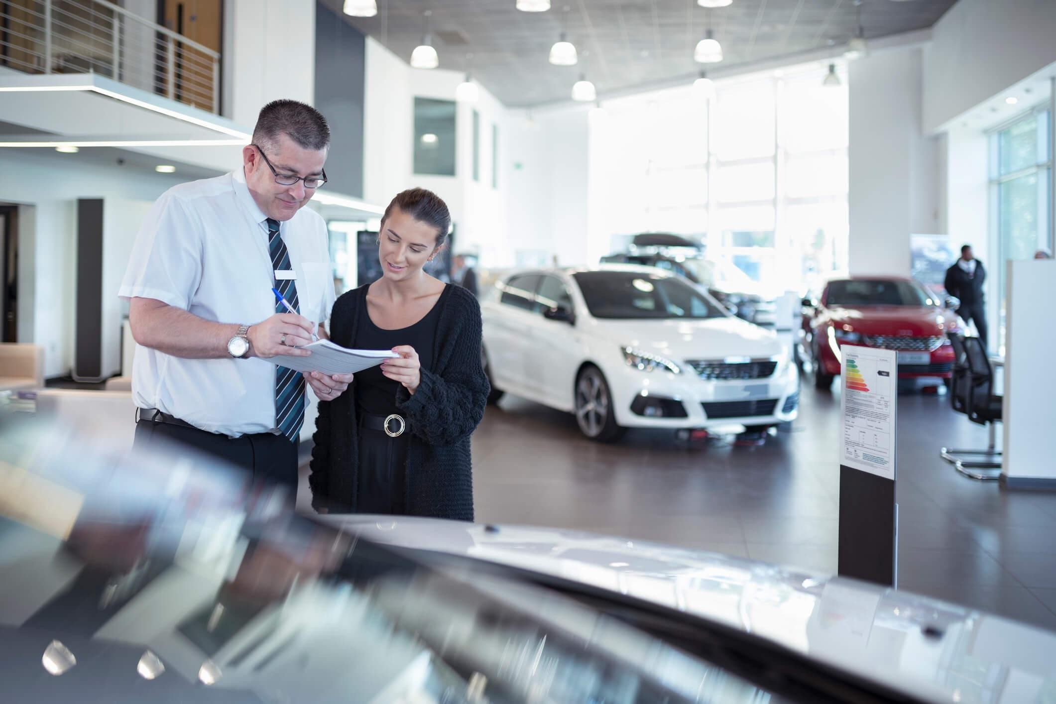 A couple is looking at the documents in a car dealership
