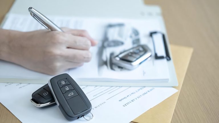 A person signing a car purchase agreement with car keys resting nearby