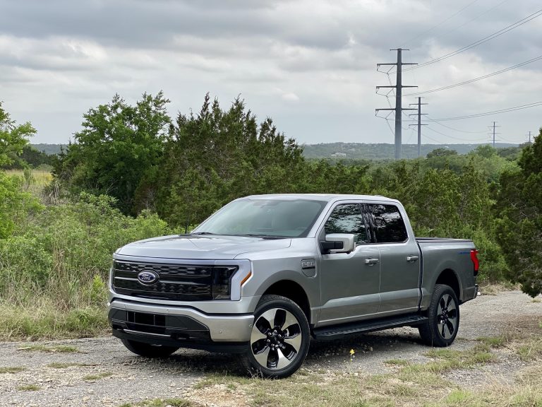A silver Ford F-150 Lightning electric pickup truck parked outdoors near utility poles