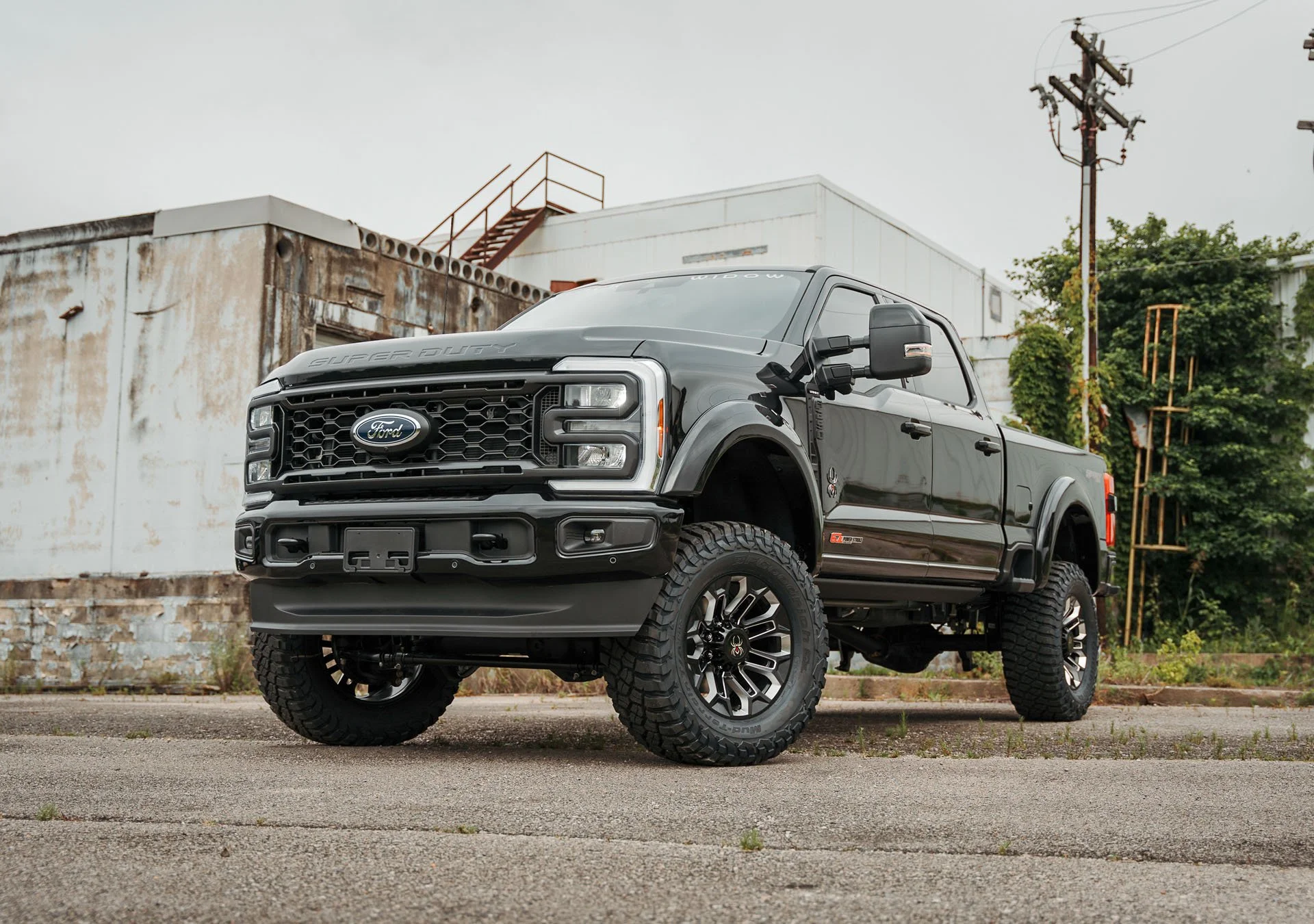 A Ford F-250 Series is standing still on the road behind a factory