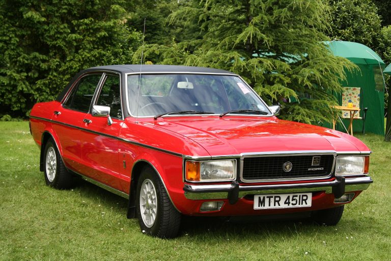 A red Ford Granada is standing on the grass