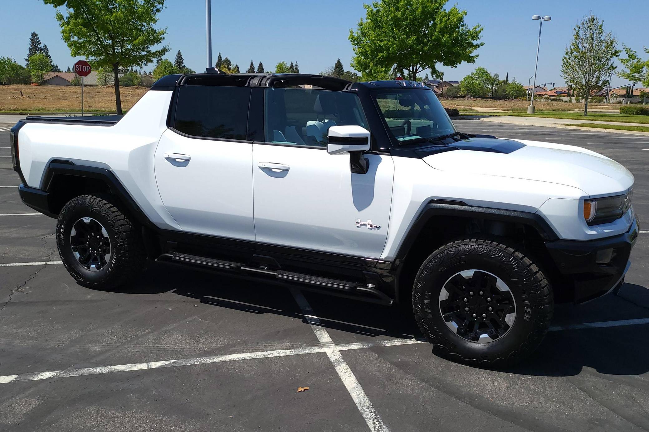 A white and black GMC Hummer EV pickup truck parked in an outdoor parking lot