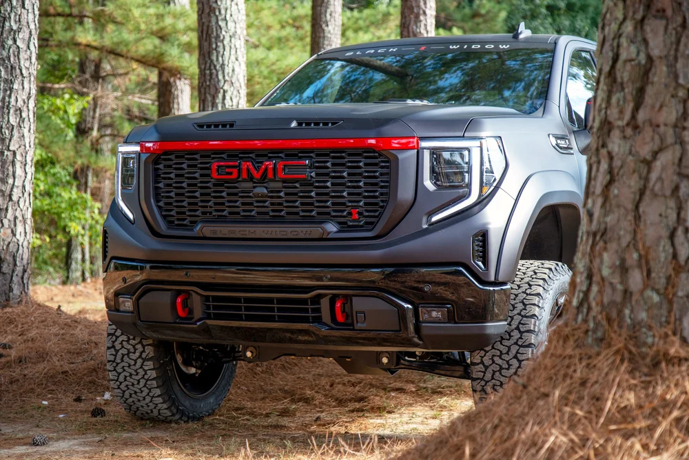 A GMC Sierra 1500 is offroading in a muddy forest
